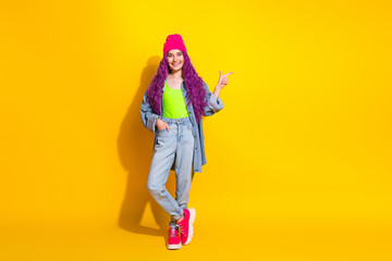 Young vibrant woman gesturing happily against a yellow background, sporting trendy fashion with dyed purple hair