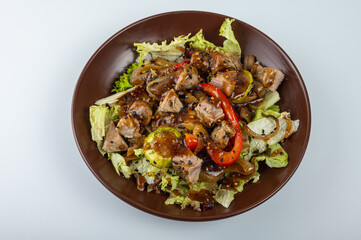 Close-up of a delicious grilled meat salad with fresh lettuce, bell peppers, onions, and sesame seeds. Gourmet dish with juicy pork, perfect for healthy eating
