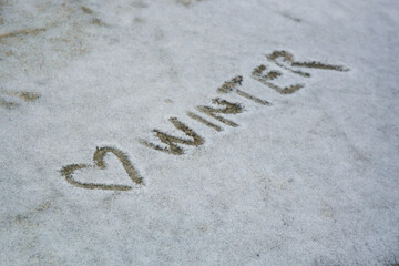 The word winter  with heart next to it  written in the snow