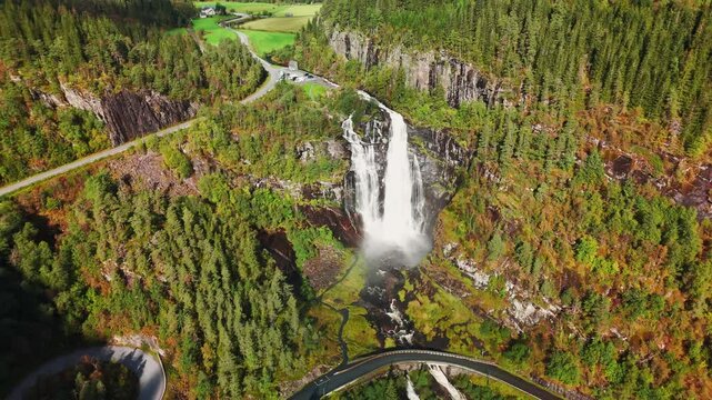 Norwegian waterfall in autumn surrounded by trees (drone footage)
