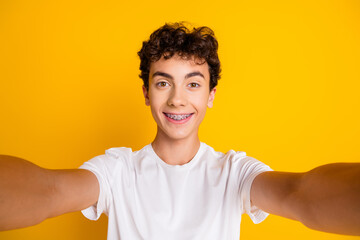 Portrait of a smiling teenage boy in a white t-shirt against a vibrant yellow background, expressing happiness and youthfulness © deagreez