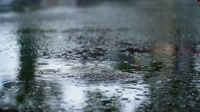 Drops of rain that fall on the asphalt when it rains. close-up rain drops. Drops of heavy rain in a puddle on the asphalt road. A Stream of water that floods all around. Rain drop splash.