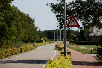 Roadway approaching a merging area surrounded by greenery in a tranquil suburban setting during the...