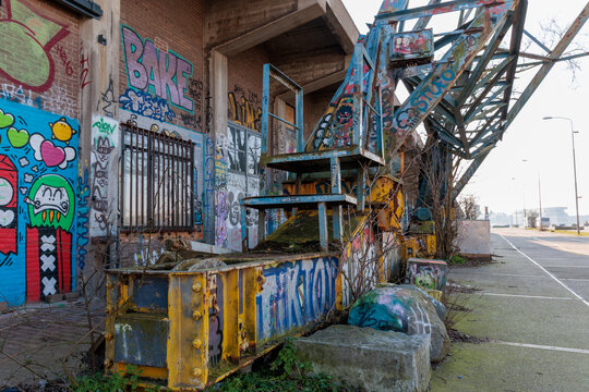 Amsterdam, The Netherlands - February 17th 2025: NDSM Wharf. A brightly colored old industrial area features a rusty crane covered in moss and vivid graffiti. The surrounding walls are adorned with va