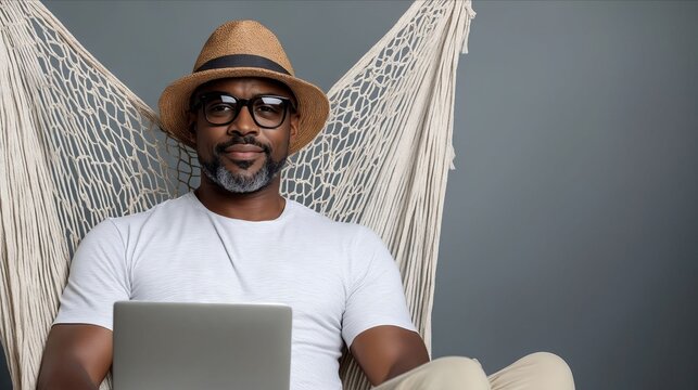 A man sitting in a hammock with a laptop - Powered by Adobe