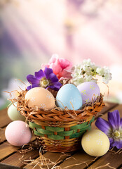Easter eggs and flowers in a basket with colorful springtime background