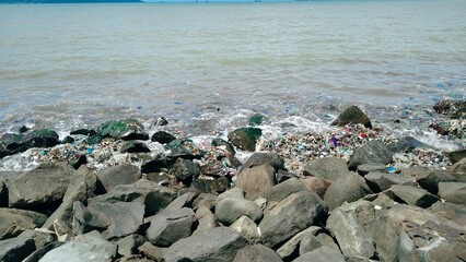 Plastic waste and debris polluting rocky shoreline, highlighting marine environmental crisis impact