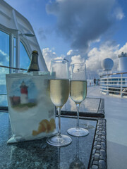 Two glasses of Champagne and a bag of chips on rattan design lounge table on outdoor deck terrace...