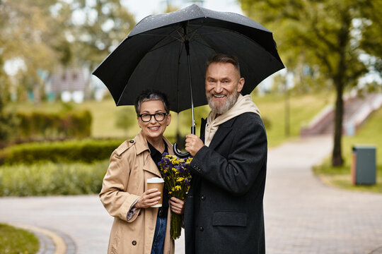 Mature couple enjoying a romantic stroll under an umbrella in a beautiful park setting