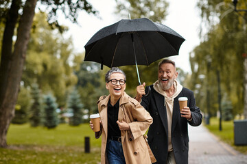 Joyful couple shares a loving moment under an umbrella on a rainy day in the park