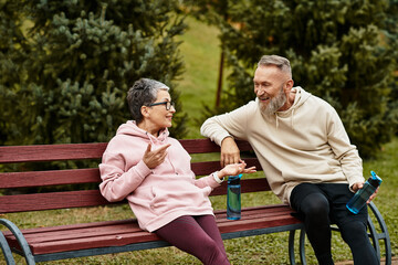 Mature couple enjoying heartfelt conversation on a park bench in the afternoon sun