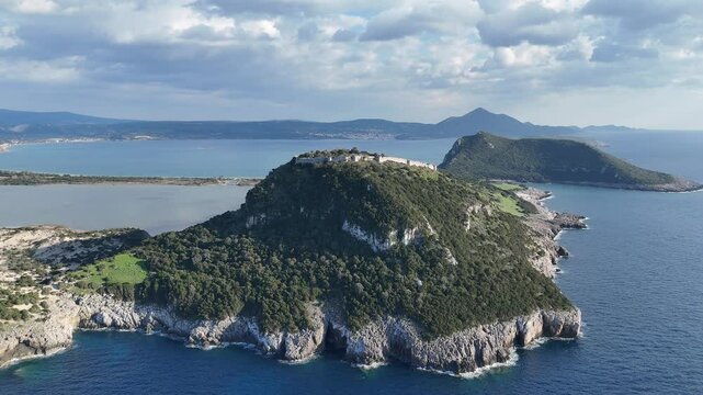 Aerial landscape view of Navarino castle ruins above colorful trees and over Voidokilia yellow sand pristine beach by Mediterranean sea, Peloponnese peninsula, Greece.
