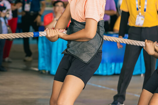 Female students participate in tug of war match. Young woman playing active games pulling rope in high school. Joyful girls playing tug of war games. Team player battle tug match for pull game.