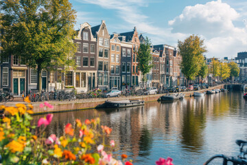 Obraz premium Traditional dutch houses reflecting on amsterdam canal with colorful flowers in the foreground