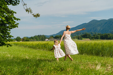 Fototapeta premium Mother and daughter in green nature. Healthy family outdoors. Woman with little girl in meadow.