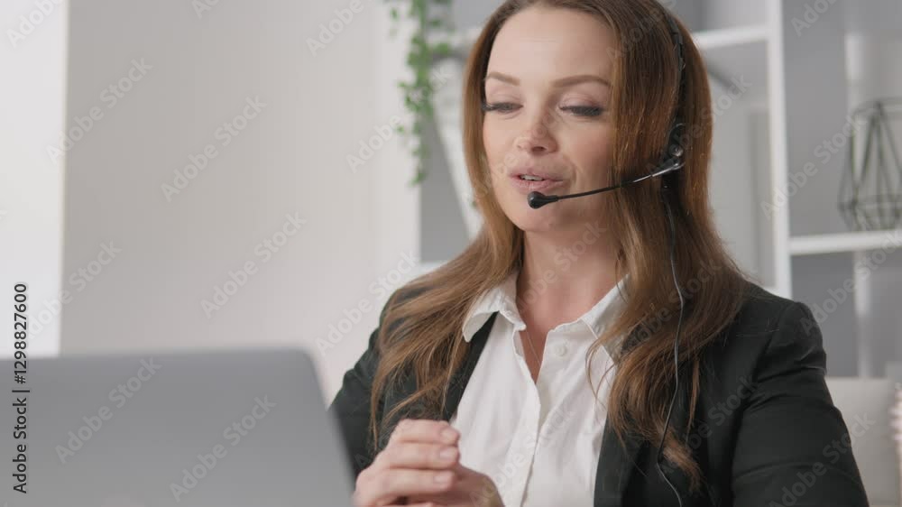 Poster A professional woman is actively engaged in virtual communication while utilizing a headset for clear audio interaction, demonstrating her multitasking skills within a corporate workspace setting