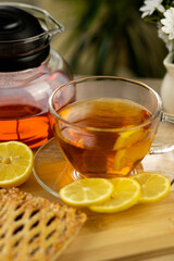 Glass cup of tea, teapot, sliced lemons on the table. Kettle with tea. Lemon tea