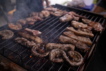 Barbecued meat is grilled on charcoal stove with various ingredients. Meat and various ingredients are grilled on charcoal stove be cooked as steak and barbecue during friends camping celebrate succes