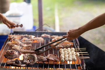 Barbecued meat is grilled on charcoal stove with various ingredients. Meat and various ingredients are grilled on charcoal stove be cooked as steak and barbecue during friends camping celebrate succes