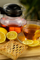 Glass cup of tea, teapot, sliced lemons on the table. Kettle with tea. Lemon tea