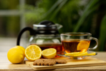 Glass cup of tea, teapot, sliced lemons on the table. Kettle with tea. Lemon tea