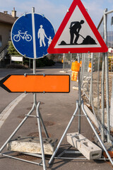 Orange deviation sign besides other signs on the road at a construction site. Construction site...