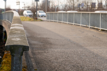 Bridge, overpass for cars and pedestriants. Close up on the metal bridge handrail, which is mossy and grungy. Traffic on the street besides the walkway for pedestriants.
