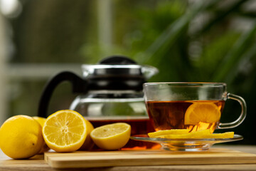 Glass cup of tea, teapot, sliced lemons on the table. Kettle with tea. Lemon tea