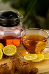 Glass cup of tea, teapot, sliced lemons on the table. Kettle with tea. Lemon tea