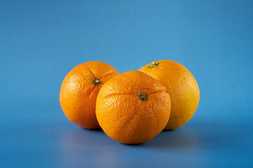 Three vibrant oranges on a blue background highlighting their texture and color