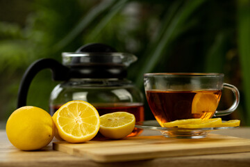 Glass cup of tea, teapot, sliced lemons on the table. Kettle with tea. Lemon tea