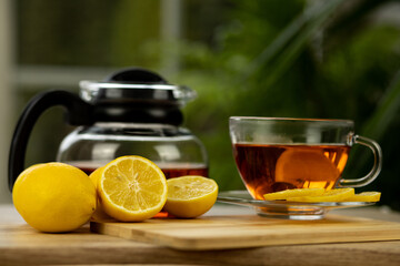 Glass cup of tea, teapot, sliced lemons on the table. Kettle with tea. Lemon tea