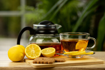 Glass cup of tea, teapot, sliced lemons on the table. Kettle with tea. Lemon tea