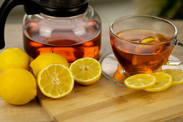 Glass cup of tea, teapot, sliced lemons on the table. Kettle with tea. Lemon tea