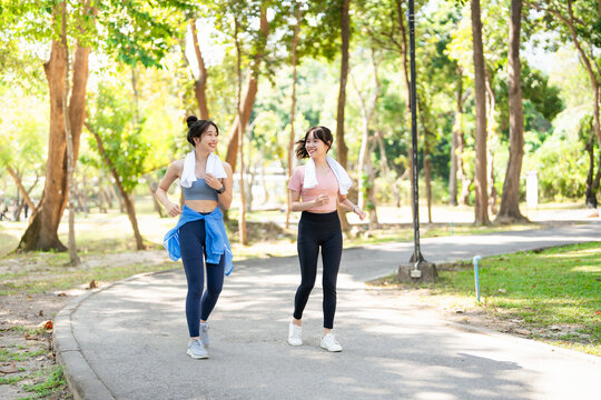 Two female friends exercising Exercise with yoga running and jogging together happily in the park Greenery in the heart of city.