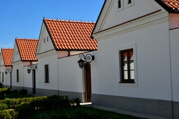 A view of an old monastery, chapel or church with numerous rooms for pilgrims and a decorative garden or square seen on a sunny summer day next to monastery walls, paths, and decorative lighting