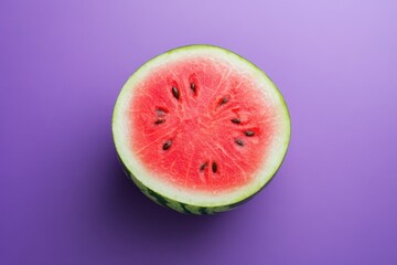 A fresh watermelon sliced in half on a purple surface