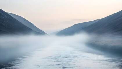 Mountains surround a body of water shrouded in thick fog