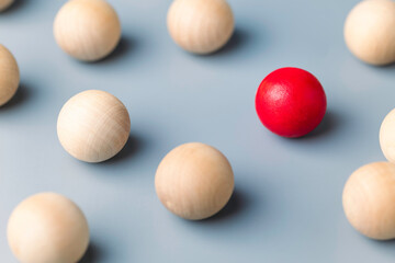 Unique red ball in the grouo of wooden red balls, being different concept, noticable in the crowd