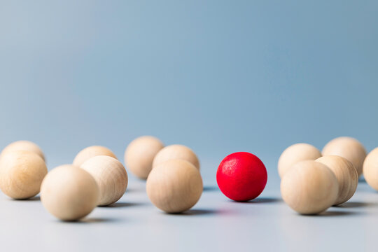 Unique red ball in the grouo of wooden red balls, being different concept, noticable in the crowd