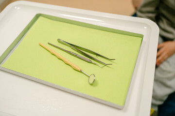 Medical dental instruments are placed on a green tray for the patient's initial examination