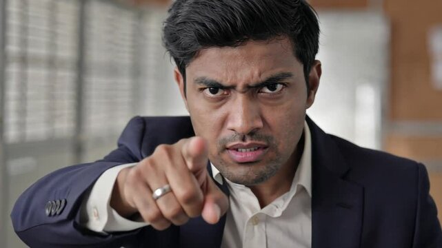 A determined Indian businessman in a suit points directly with an intense expression. Concept of leadership, urgency, and taking action in the corporate world.