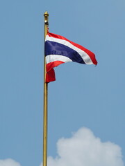 Thai flag waving on flagpole,  The siam flag flutters in the wind. The Thai national flag  has a sky and white clouds backdrop. Flag has 5 stripes, 3 colours: blue, red, white. Winds blew up.
