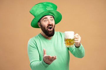 Bearded man wearing leprechaun hat drinking beer celebrating St. Patrick's Day
