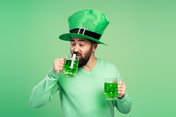 Man wearing leprechaun hat drinking green beer celebrating St. Patrick's Day