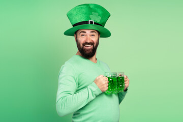 Bearded man wearing leprechaun hat holding green beer for St. Patrick's Day celebration