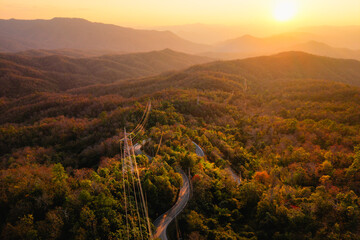 Mountain landscapes reveal scenic sunrises and sunsets painting the sky with clouds over forested...