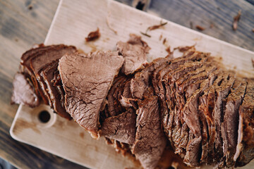 Slices of juicy roast beef lie in a row on a cutting board