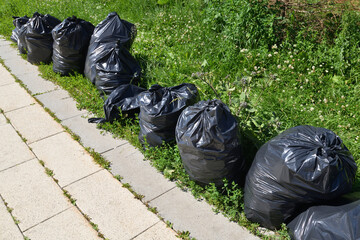 Black bags of garbage line the sidewalk.