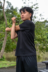 Young Asian male sportsman doing warm up  exercise in green nature park